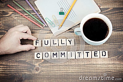 Fully committed. Wooden letters on the office desk Stock Photo