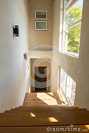 Rustic wooden staircase with large windows that sunlight passes through Stock Photo