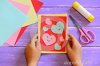 Child is holding a Valentines day card in his hands. Small child made a Valentines day greeting card. Cute and simple paper crafts Stock Photo
