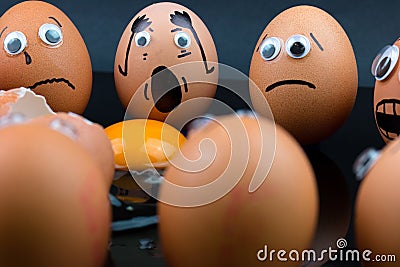 Fun concept: raw eggs with googly eyes and drawn features in shock witness another egg broken in front of them Stock Photo