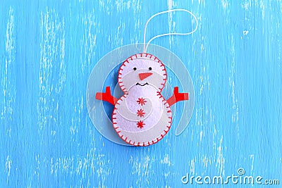 Fun felt Christmas snowman ornament isolated on a blue wooden background. How to make a Christmas snowman ornament. Step Stock Photo