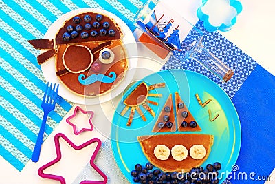 Fun food for kids. Pancakes with berries, pirate and ship boat. Creative breakfast for children. Stock Photo