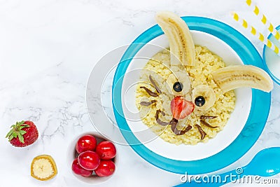 Fun and healthy breakfast idea for kids - Easter bunny millet porridge with milk, chocolate, banana and strawberry Stock Photo