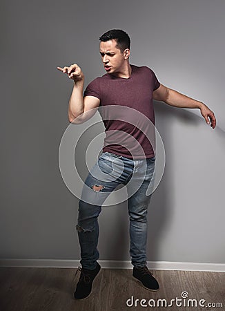 Fun humor grimacing young man showing crazy duck pose and making fun on grey background. Closeup Stock Photo