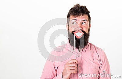 Fun and laugh concept. Man holding paper party props smiling lips, white background. Hipster with beard and mustache on Stock Photo