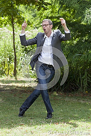 Fun modern businessman enjoying job promotion in green park Stock Photo