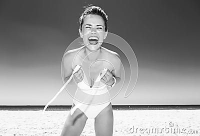 Smiling young woman in swimsuit on seacoast dressing swimsuit Stock Photo