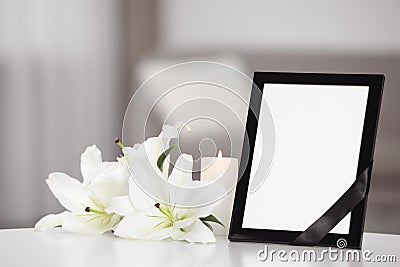 Funeral photo frame with black ribbon and lilies on white table indoors Stock Photo