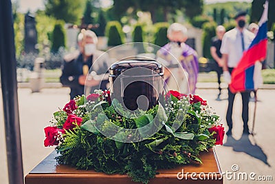 Funerary urn with ashes of dead and flowers at funeral Stock Photo