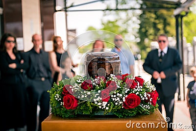 Funerary urn with ashes of dead and flowers at funeral Stock Photo