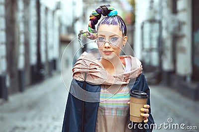 Funky hipster young girl tourist walking city streets holding to go coffee Stock Photo