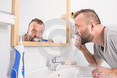 Man brushing his teeth in bathroom Stock Photo