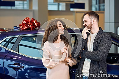 Funnny woman pressing her palms, begging her boyfriend to buy a vehicle for her Stock Photo
