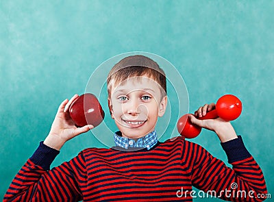 Funny active schoolboy excercising holding an apple and a dumbbell Stock Photo