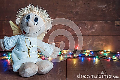 Funny angel and bright lights garlands on wooden boards Stock Photo