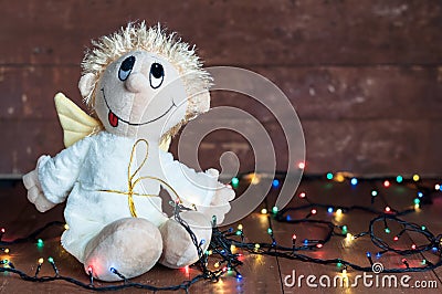 Funny angel and bright lights garlands on wooden boards Stock Photo