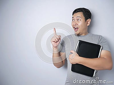 Funny Asian Man Holding Laptop, Thinking and Smiling For Having Good Idea Stock Photo