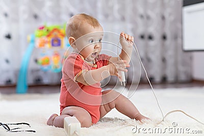Baby boy pulling cables from electrical extension Stock Photo