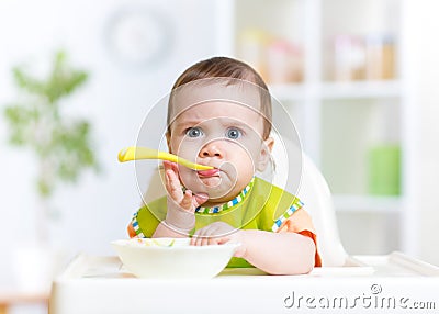 Funny baby eating food on kitchen Stock Photo