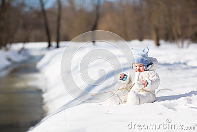 Funny baby playing at a snowy river Stock Photo