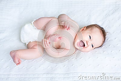 Funny baby wearing diaper playing with her feet Stock Photo