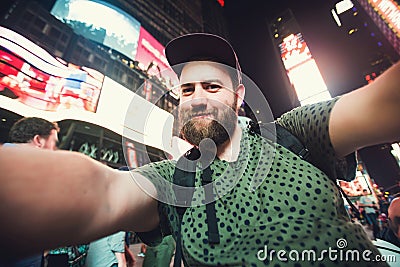 Funny bearded man backpacker smiling and taking selfie photo on Times Square in New York while travel across USA Stock Photo