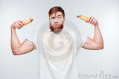 Funny bearded man in filthy shirt holding to hotdogs Stock Photo