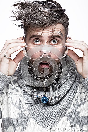 Funny bearded man in a New Year`s image with snow and decorations on his beard. Feast of Christmas. Stock Photo