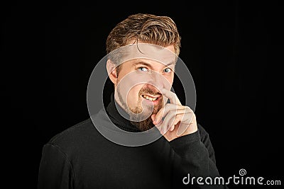 Funny bearded man picking his nose, black background Stock Photo