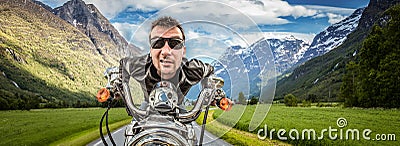 Funny Biker in sunglasses and leather jacket racing on mountain Stock Photo