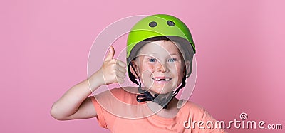 Funny blond kid in helmet missing tooth giving thumb up sign. Child with two upper missing teeth isolated on pink Stock Photo