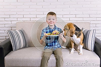 Funny boy with dog beagle eating fried potatoes with a hamburger Stock Photo