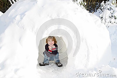 Funny boy in snow igloo on a sunny winter day Stock Photo