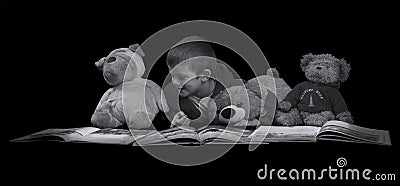 Funny boy with stuffed animals reading a book before bed time ar Stock Photo