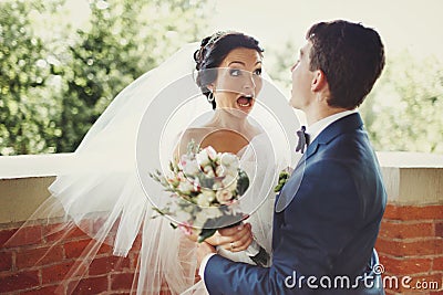 Funny bride looks shocked being hugged by a groom Stock Photo