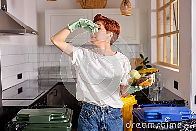 eco-friendly caucasian female in casual wear throwing spoiled fruit into waste bins cans Stock Photo