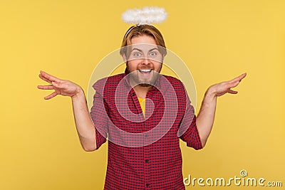 Funny cheerful bearded guy with saint nimbus over head raising hands as wings flying up, pretending angel, looking at camera Stock Photo