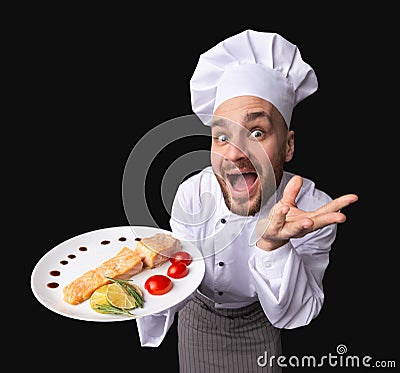 Funny Chef Offering Salmon Dish On Plate, Studio Shot, High-Angle Stock Photo