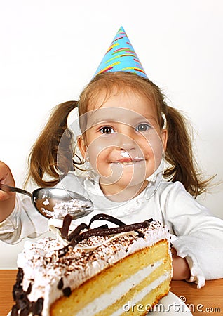 Funny child girl with birthday hat eating cake Stock Photo