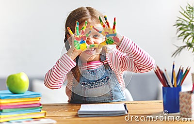 Funny child girl draws laughing shows hands dirty with paint Stock Photo