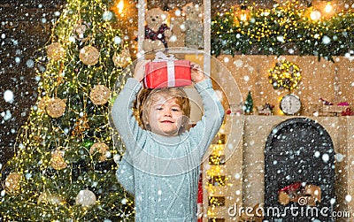 Funny child holding a red gift box with both hands. Christmas Celebration holiday. Happy little child dressed in winter Stock Photo