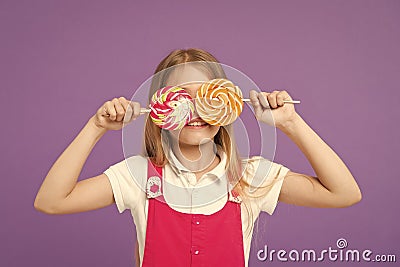 Funny child with lollipops on violet background. Little kid smile with candies on sticks on purple background. Girl Stock Photo