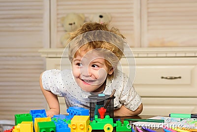 Funny child plays in the constructor in playroom, kids funny face. Kids playing with colorful blocks, head portrait. Stock Photo