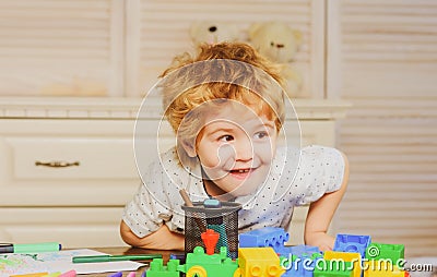 Funny child plays in the constructor in playroom, kids funny face. Kids playing with colorful blocks, head portrait. Stock Photo