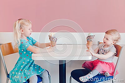 Funny children girls sitting together bragging boasting their ice-cream Stock Photo
