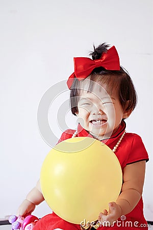 Funny Chinese little baby in red cheongsam play yellow balloon Stock Photo