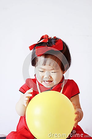 Funny Chinese little baby in red cheongsam play yellow balloon Stock Photo