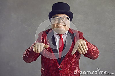 Funny chubby rich senior man in shiny jacket and black top hat dancing and smiling Stock Photo