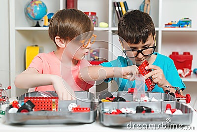 Funny classmates doing creative mechanical robot. Clever children creating diy construction at the table Stock Photo