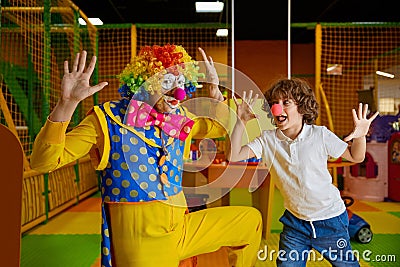Funny clown animator and boy fooling around playing at indoor playroom Stock Photo